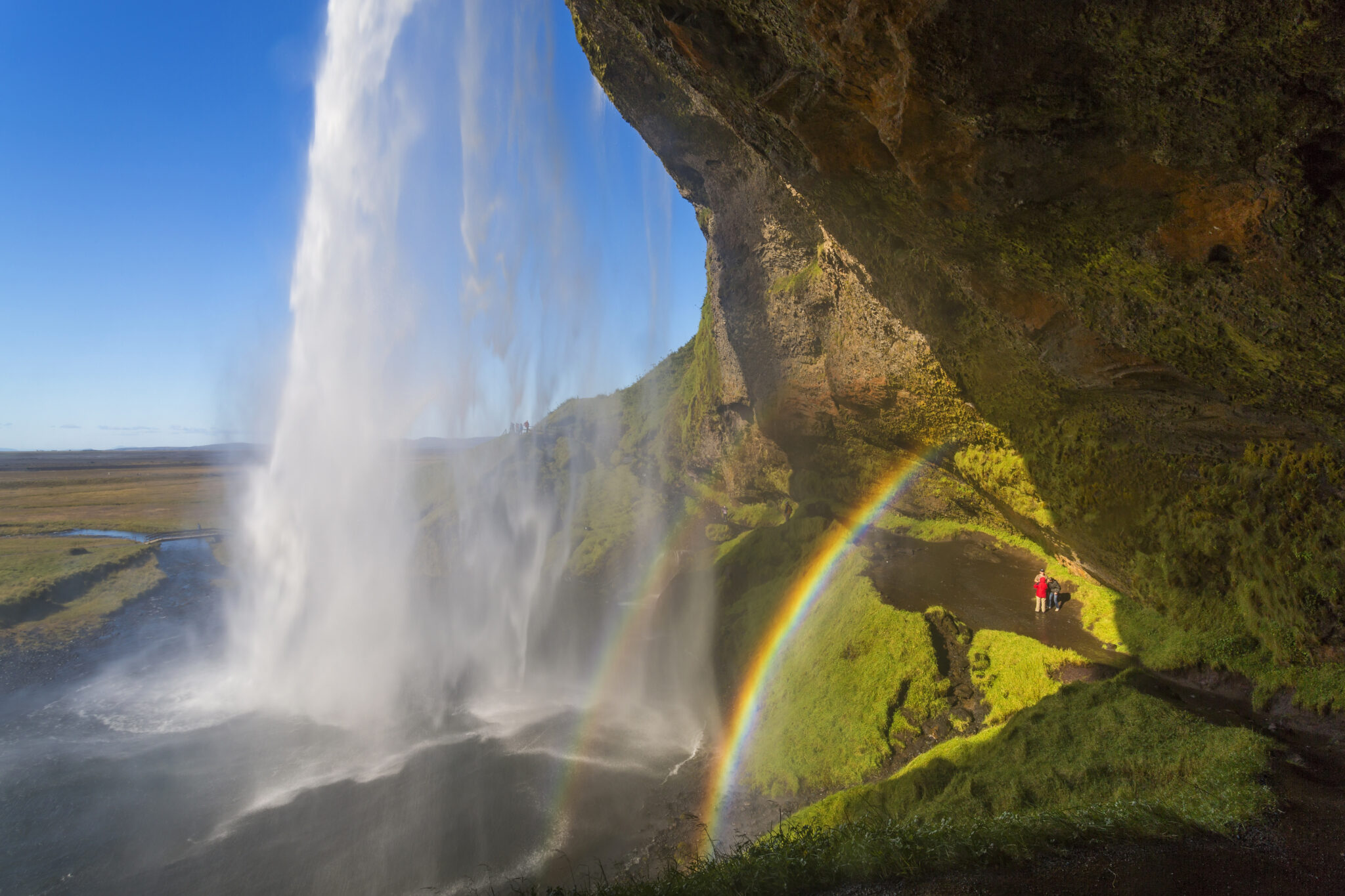 A waterfall cascade over a sheer cliff, a double rainbow in the mist.