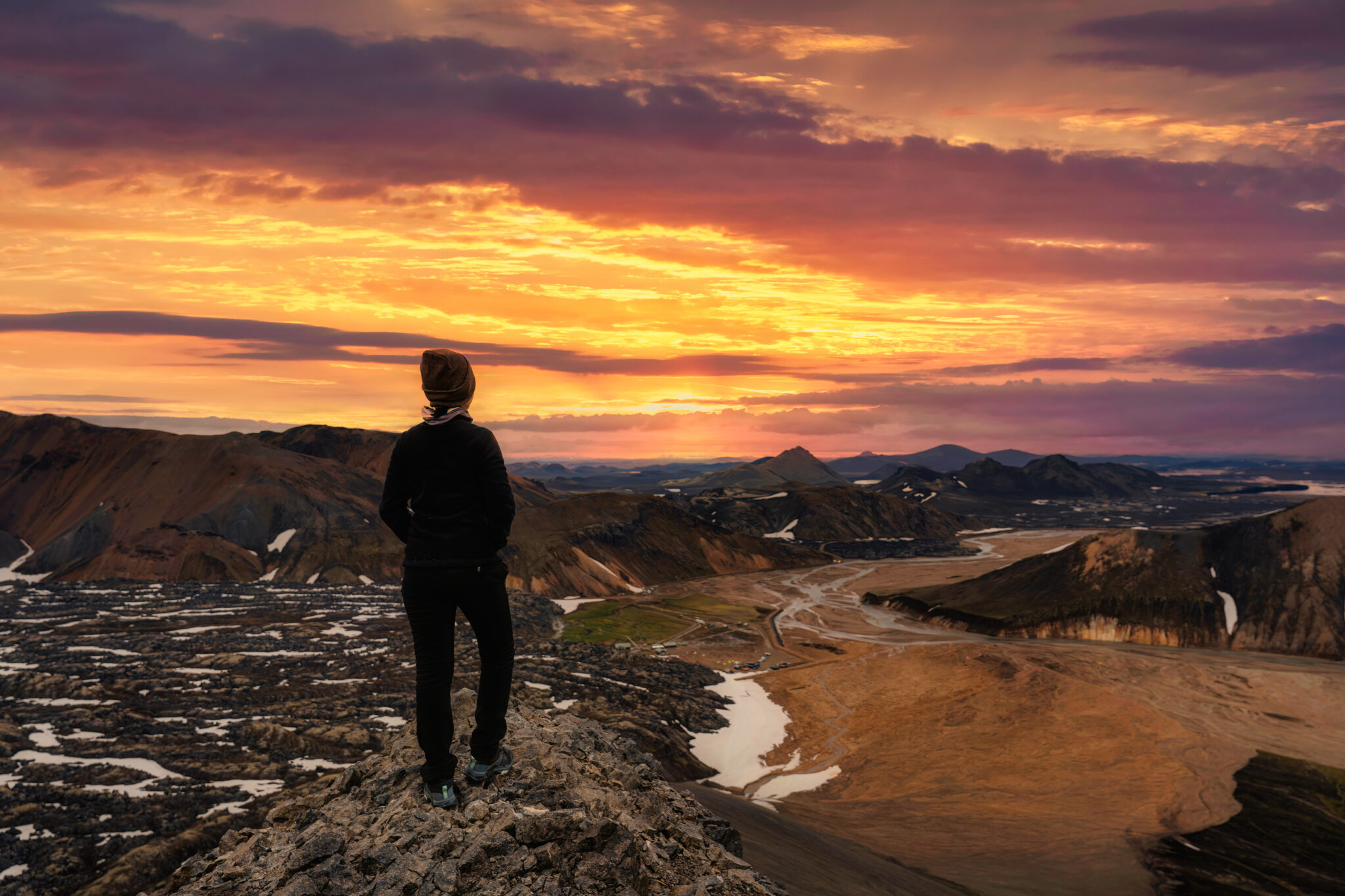 Hiker young female standing on volcanic mountain and sunset sky from Blahnjukur trail on summer at Icelandic Highlands